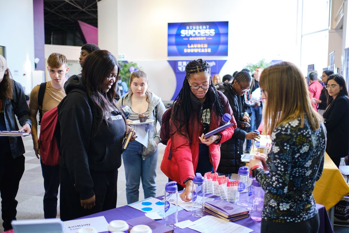 Students looking at materials on a desk at a Student Success Academy event